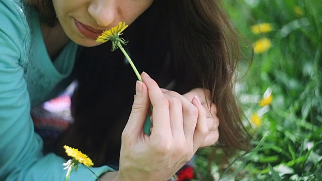 《草地上的美女》美丽的年轻女孩户外。享受大自然。健康微笑的女孩躺在绿草和野花。笑和快乐视频素材