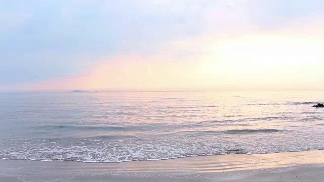 热带海岸海滩上的日出。海水冲刷着海滩，海浪慢慢地拍打着沙滩。视频素材