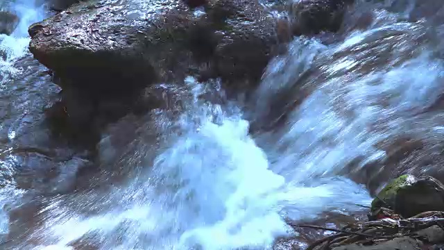 近距离观察瀑布在山上森林的石头上流动视频素材
