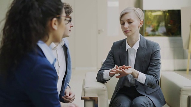 女商人坐在现代办公中心的沙发上与商业伙伴讨论未来的合同视频素材