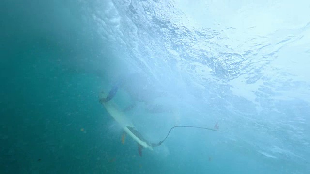 水下:极限冲浪者在汹涌的深蓝色海浪中做危险的鸭子潜水。视频素材