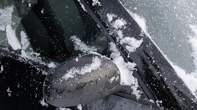 年轻人正在用刷子清理车上的雪。视频素材