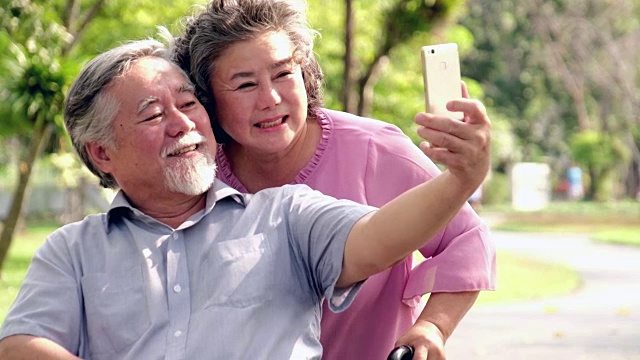 老女人在户外推着轮椅上的男人。视频素材