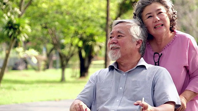 老女人在户外推着轮椅上的男人。视频素材