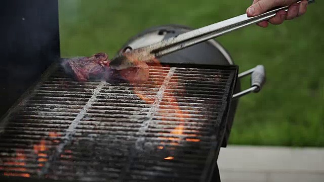 男人把肉排放在烤架上视频素材