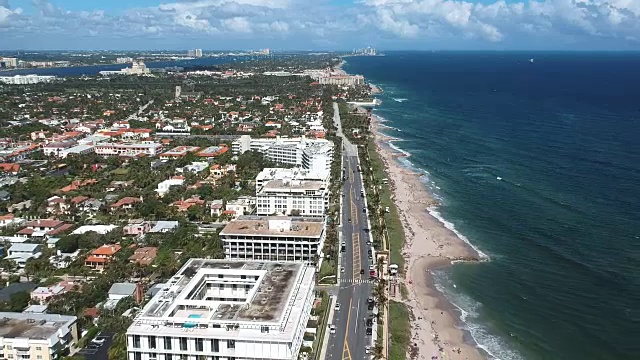 无人机拍摄向后飞在棕榈滩，佛罗里达与度假胜地，海滩，海岸线，和繁忙的街道下面。视频素材