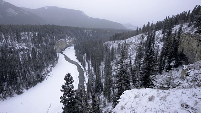 冰冷的冬季河流在暴风雪中蜿蜒穿过峡谷山谷视频下载