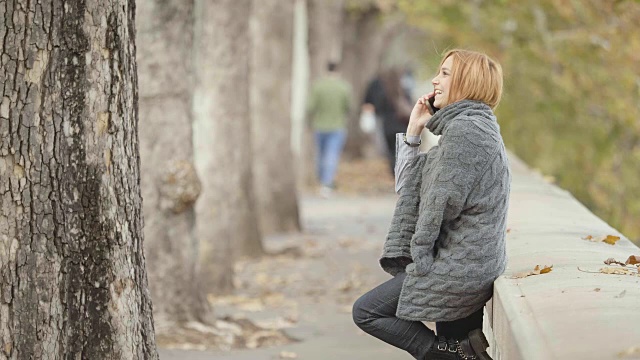 在人行道上打电话。在寒冷的天气里在街上微笑的女士视频素材