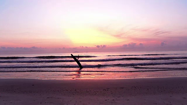 热带海岸海滩上的日出。海水的波浪涌上海滩，海浪慢慢地拍打着沙滩。视频素材