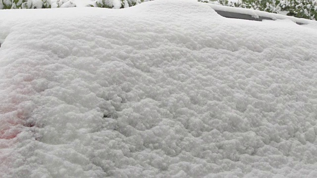 一辆被雪覆盖的汽车上的爱情告白——一名女子正在一辆被雪覆盖的汽车的后车窗上画一个心形视频素材