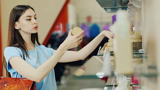 一个年轻的女人带着化妆品走到窗前，拿了一罐奶油和树叶视频素材