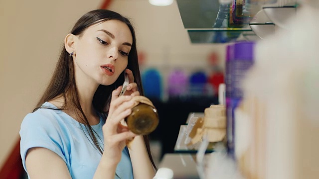 年轻女子一边打电话，一边在香水部挑选商品视频素材