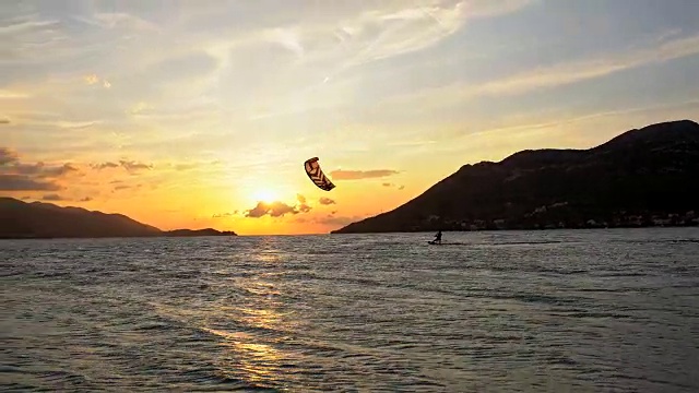 日落时，风筝滑板者在海浪上冲浪视频素材