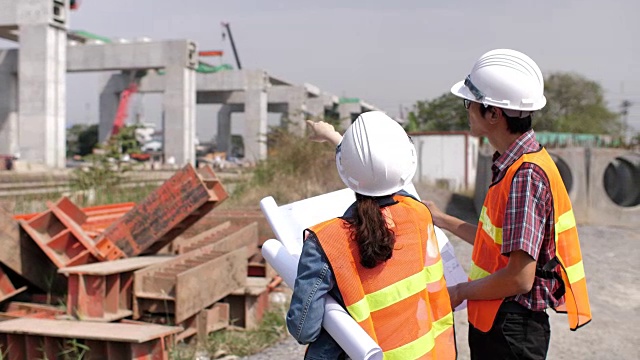 建筑师和工程师拿着设计图和手电筒在建筑工地交谈视频素材