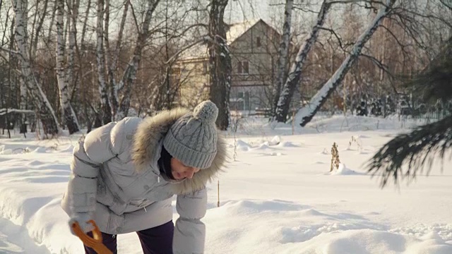 在郊区的冬天，年轻女子用铁铲铲雪视频素材