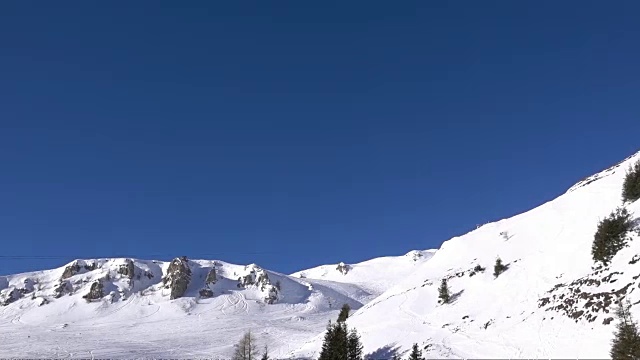 空中的慢动作镜头在蓝天上的雪山山脊山谷。视频素材