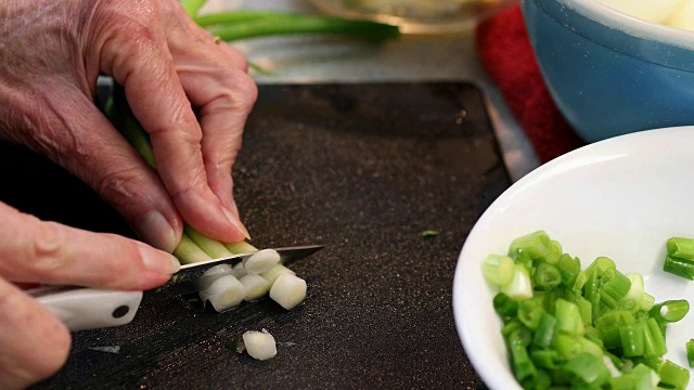 在切菜板上切绿洋葱。细香葱视频素材