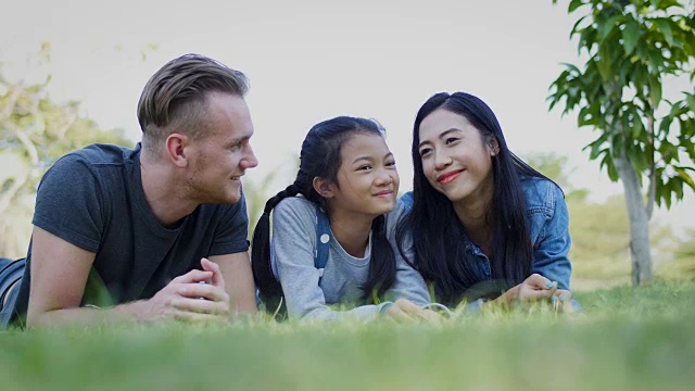 幸福的家庭躺在户外公园的草地上，人们和生活方式的概念视频素材