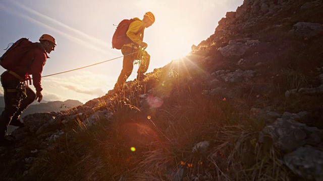 两名登山队员组成的绳索队在夕阳下爬山视频购买