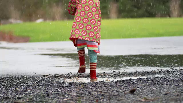 小女孩撑着伞在雨中嬉戏，慢镜头视频素材