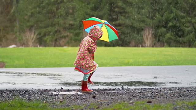 小女孩撑着伞在雨中嬉戏，慢镜头视频素材