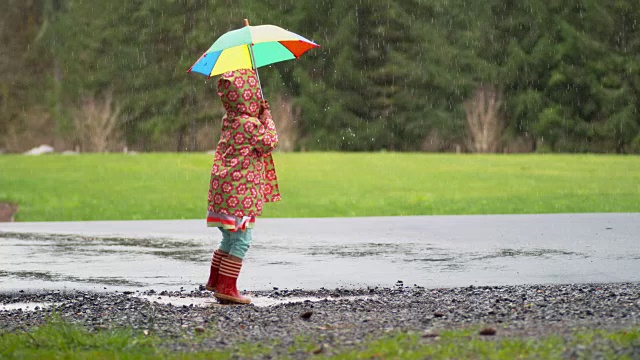 小女孩撑着伞在雨中嬉戏，慢镜头视频素材