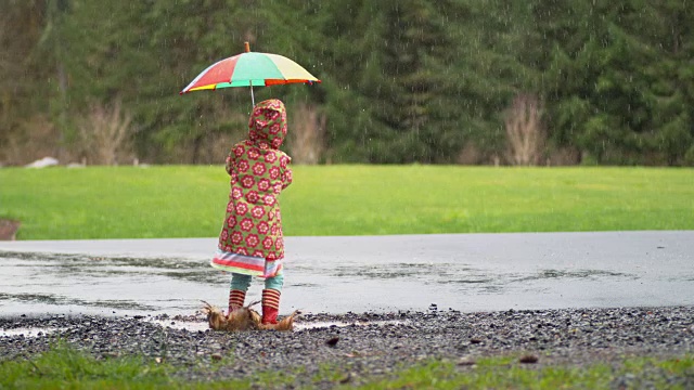 小女孩撑着伞在雨中嬉戏，慢镜头视频素材