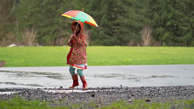 小女孩撑着伞在雨中嬉戏，慢镜头视频素材