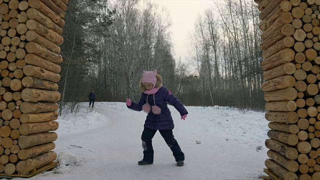 冬天，小女孩在雪地上跳着滑稽的舞蹈，在森林里散步视频素材