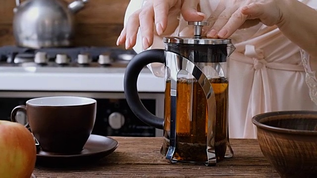 女性用手把热茶从茶壶里倒进了茶杯里。视频素材