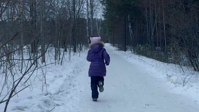 奔跑的少女在冬天的雪林里玩耍，走回来看慢镜头。视频素材