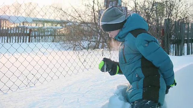 一个少年在冬天的公园里画着雪地里的冰柱。有雪有霜的晴天。新鲜的空气里充满了乐趣和游戏。视频素材