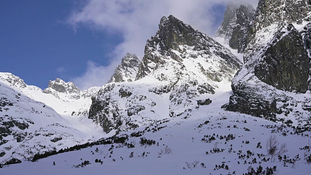 在寒冷的阳光明媚的天气里，滑雪游览覆盖在雪中的岩石山脉景观视频素材