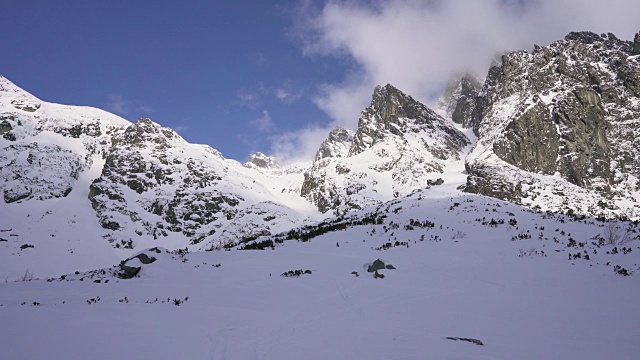 在寒冷的阳光明媚的天气里，滑雪游览覆盖在雪中的岩石山脉景观视频素材