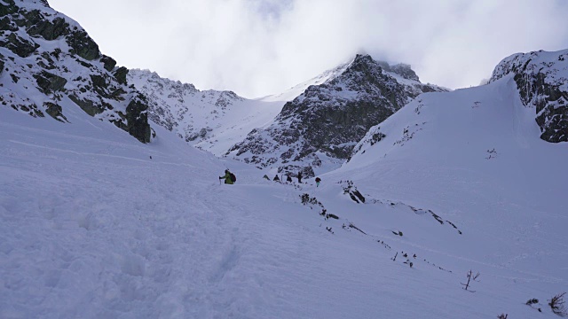 在寒冷的阳光明媚的天气里，滑雪游览覆盖在雪中的岩石山脉景观视频素材