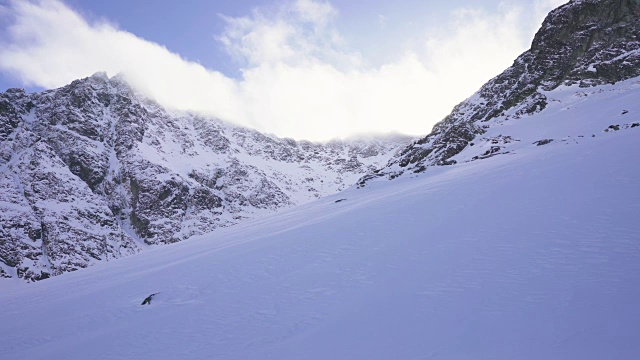 在寒冷的阳光明媚的天气里，滑雪游览覆盖在雪中的岩石山脉景观视频素材