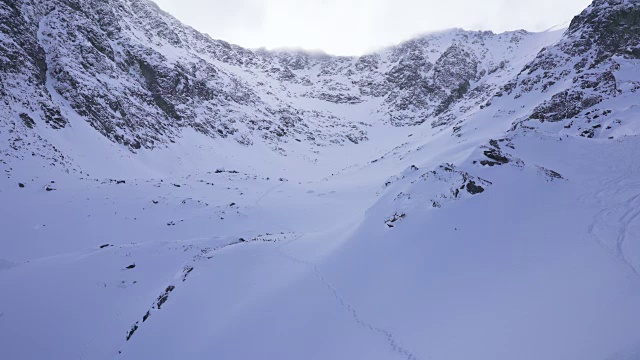 在寒冷的阳光明媚的天气里，滑雪游览覆盖在雪中的岩石山脉景观视频素材