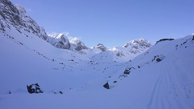 在寒冷的阳光明媚的天气里，滑雪游览覆盖在雪中的岩石山脉景观视频素材