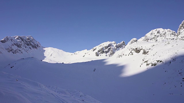 在寒冷的阳光明媚的天气里，滑雪游览覆盖在雪中的岩石山脉景观视频素材