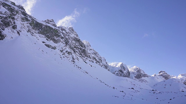 在寒冷的阳光明媚的天气里，滑雪游览覆盖在雪中的岩石山脉景观视频素材