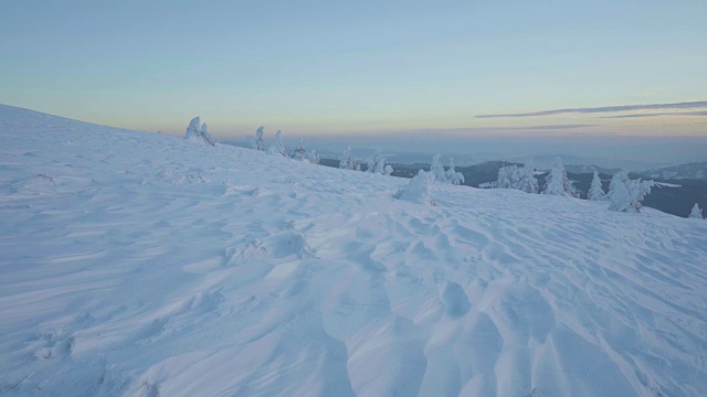 冬季日落时，冰雪覆盖的景观和山上的树木视频素材