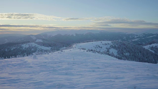 冬季日落时，冰雪覆盖的景观和山上的树木视频素材