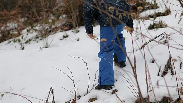 森林里的男孩。雪地里的脚步声。蓝色裤子，棕色头发。害怕和孤独视频素材