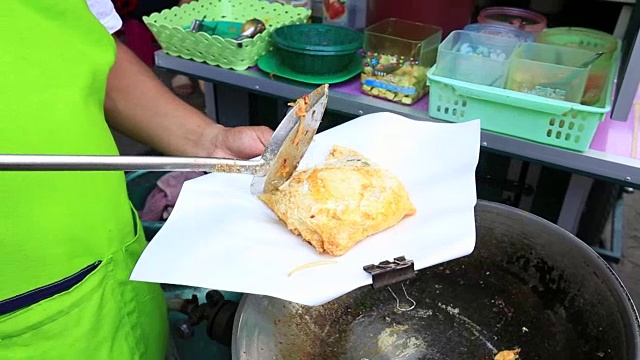 一名男子正在泰国的小吃街市场上做鸡蛋泰式炒面视频素材