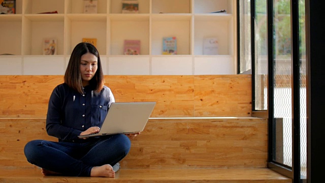 年轻女子使用她的笔记本电脑打字键盘在家里工作视频素材