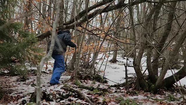 森林里的男孩。雪地里的脚步声。蓝色裤子，棕色头发。害怕和孤独视频素材