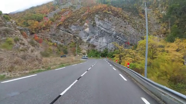 在法国，骑摩托车的人在风景山岩路上行驶。多雨的天气。第一个人的观点视频素材