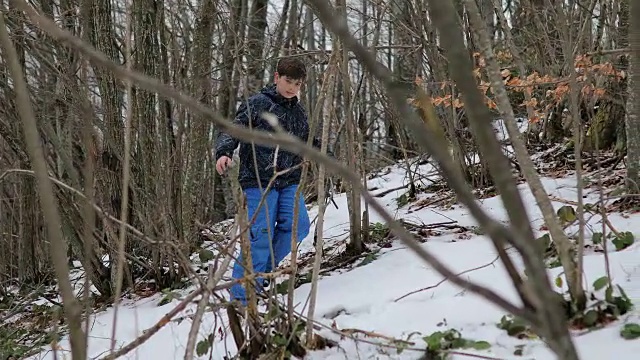 森林里的男孩。雪地里的脚步声。蓝色裤子，棕色头发。害怕和孤独视频素材