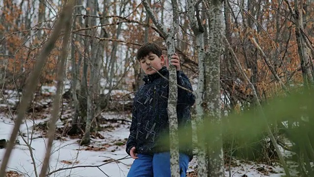 森林里的男孩。雪地里的脚步声。蓝色裤子，棕色头发。害怕和孤独视频素材