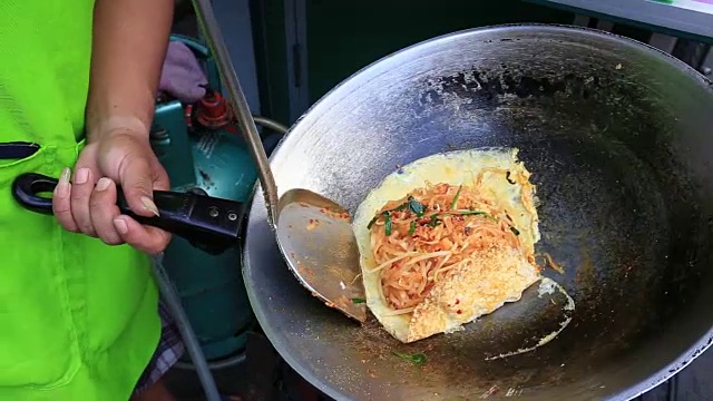 一名男子正在泰国的小吃街市场上做鸡蛋泰式炒面视频素材